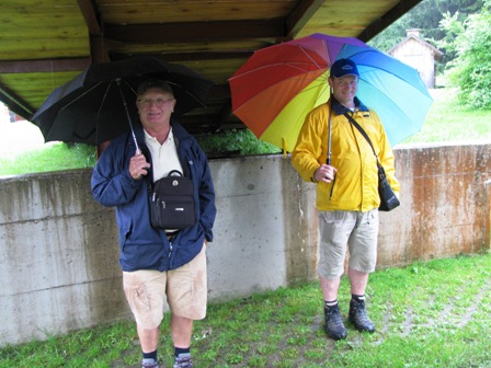 Diese Wanderer suchen Schutz mit Regenschirm unter der Brücke vor der K+L beim Museum