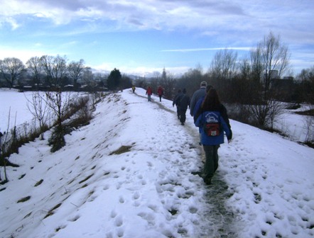 Wanderer am schneebedeckten Weg entlang der Traisen