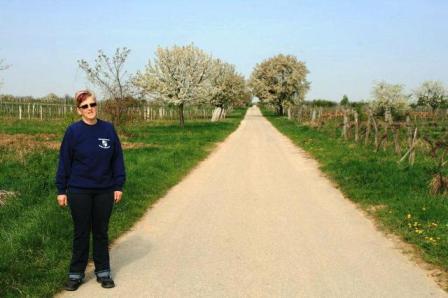 Renate vor einer langen Geraden mit Obstbäumen